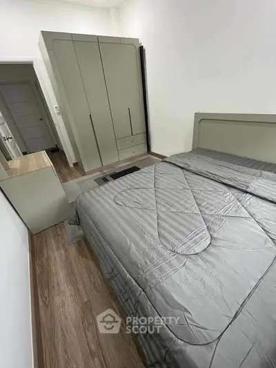 Modern bedroom with sleek grey bedding and built-in wardrobe for stylish living.