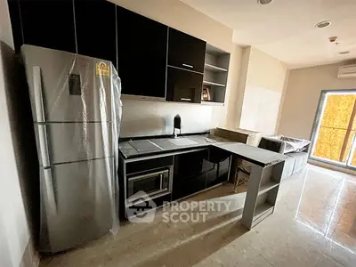 Modern kitchen with sleek black cabinets and stainless steel appliances in a stylish apartment.