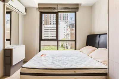 Bright bedroom with large window and modern furnishings in urban apartment.