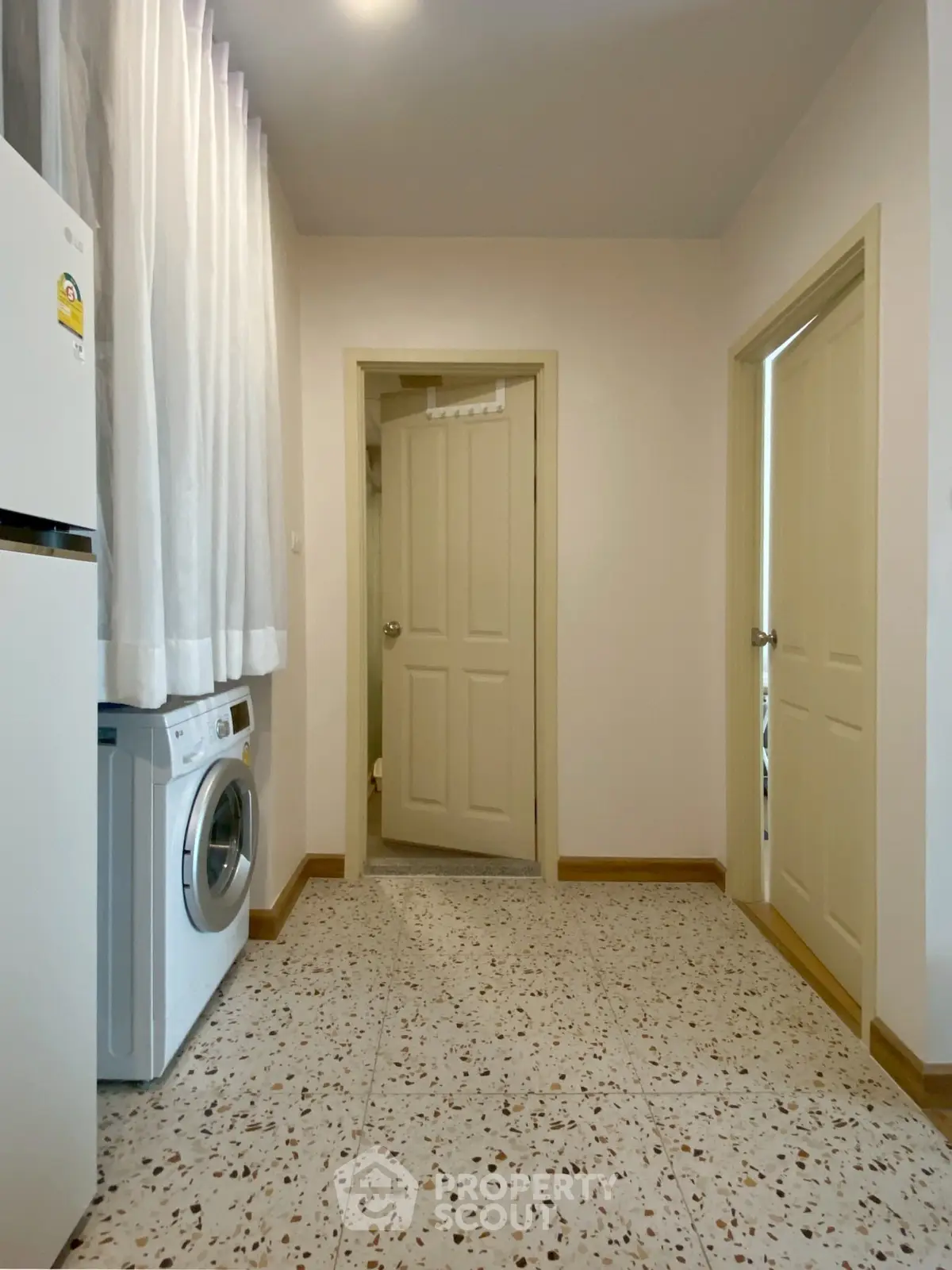 Spacious laundry area with washing machine and fridge in modern home.