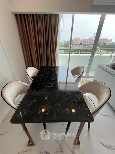 Elegant dining area with marble table and city view from balcony in modern apartment.