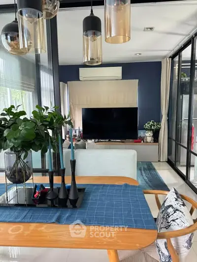 Modern living room with stylish decor, large TV, and elegant dining area, perfect for contemporary living.