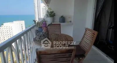 Charming balcony with ocean view, wooden furniture, and decorative plants in a high-rise apartment.