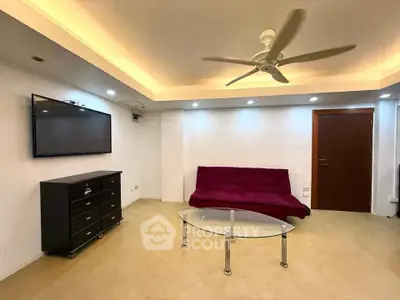Modern living room with sleek furniture and ambient lighting, featuring a ceiling fan and wall-mounted TV.
