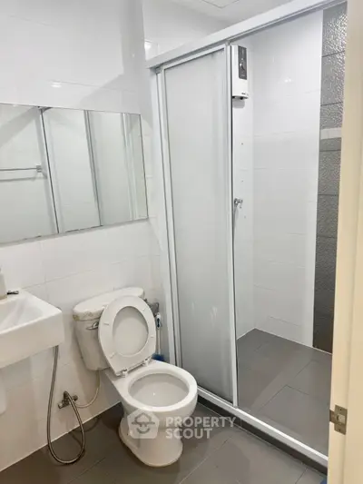Modern bathroom with shower and toilet in sleek white and gray design.