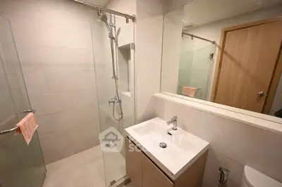 Modern bathroom with glass shower and sleek vanity in a contemporary home.