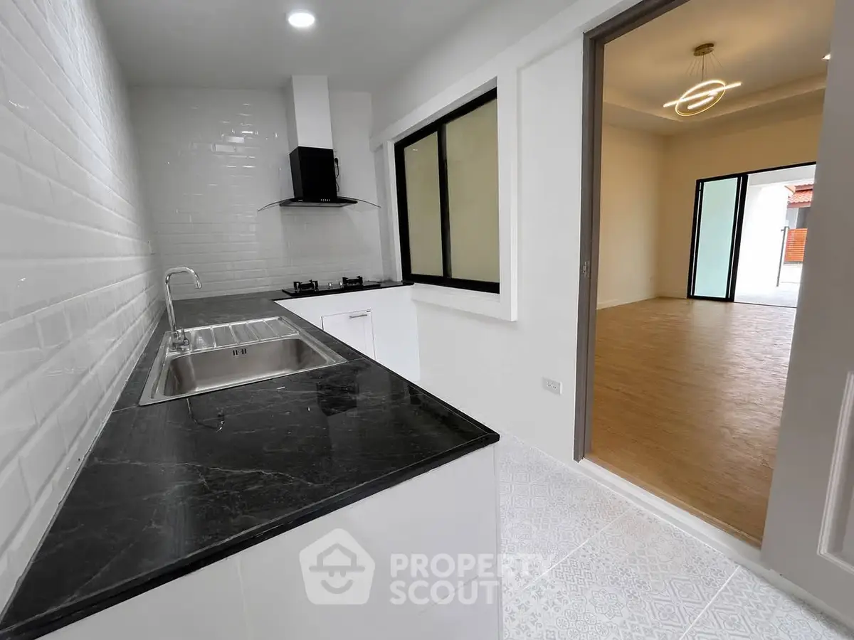 Modern kitchen with sleek black countertop and open layout to spacious living area.