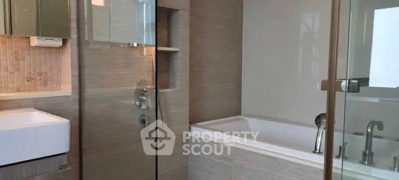 Modern bathroom with sleek design featuring bathtub and glass shower enclosure.