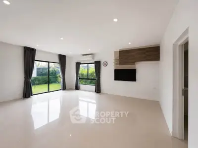Spacious modern living room with large windows and garden view, perfect for family gatherings.