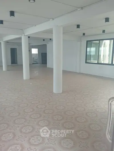 Spacious open-plan interior with tiled flooring and large windows, ideal for versatile use.