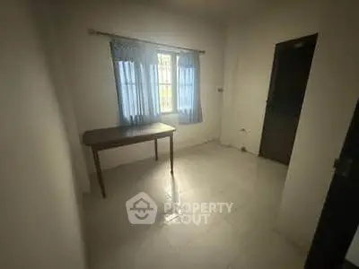 Minimalist room with a window and simple table, ideal for study or small office space.