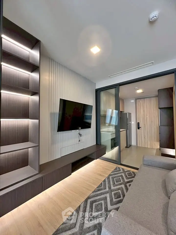 Modern living room with sleek design, built-in shelves, and open kitchen layout in a stylish apartment.