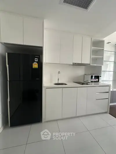 Modern kitchen with sleek white cabinets and black fridge