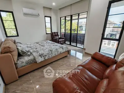 Spacious bedroom with large windows and balcony access, featuring modern furnishings and natural light.
