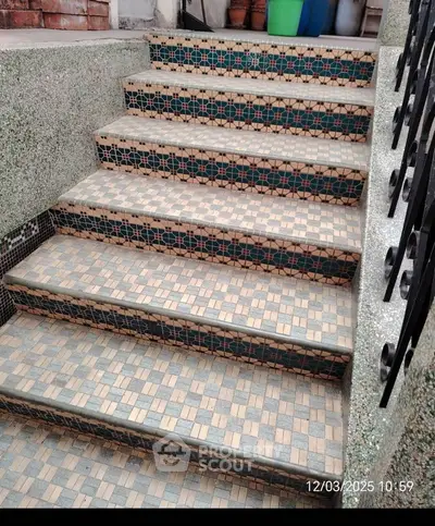 Stylish outdoor tiled staircase with intricate geometric patterns and wrought iron railing.