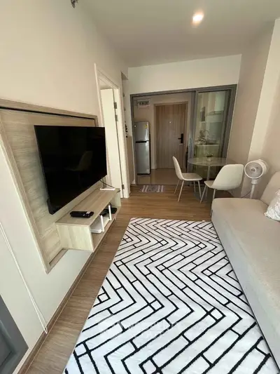 Modern living room with stylish decor and open layout, featuring a wall-mounted TV and cozy seating area.