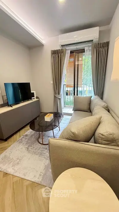 Cozy living room with modern sofa, TV, and balcony view in stylish apartment.