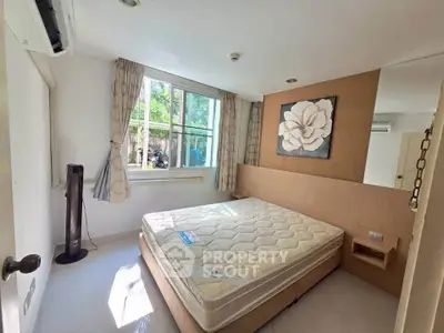 Bright bedroom with large window and modern decor, featuring a comfortable bed and stylish wall art.