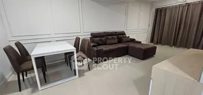 Modern living room with sleek dining set and plush brown sofa