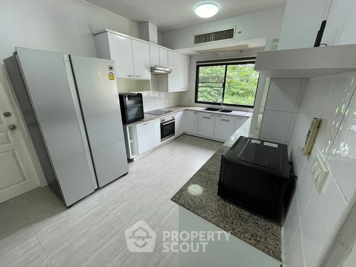 Spacious modern kitchen with sleek appliances and large window view.