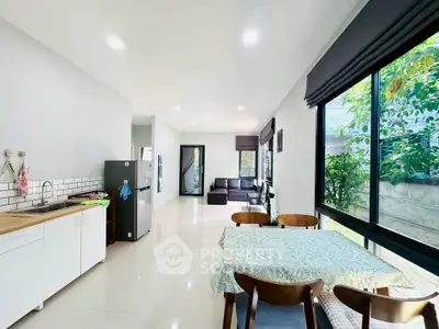 Spacious open-plan living and dining area with modern kitchen and large windows.