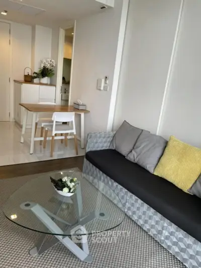 Modern living room with stylish furniture and glass coffee table in a cozy apartment setting.
