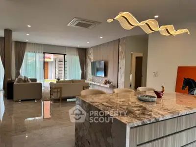 Luxurious open-plan living room with marble floors and modern lighting, featuring a spacious seating area and elegant decor.