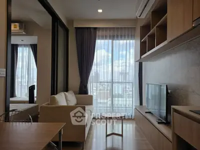 Modern living room with natural light, cozy sofa, and sleek TV setup in a stylish apartment.