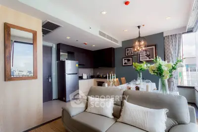 Modern living room with open kitchen, stylish decor, and large windows offering city views.