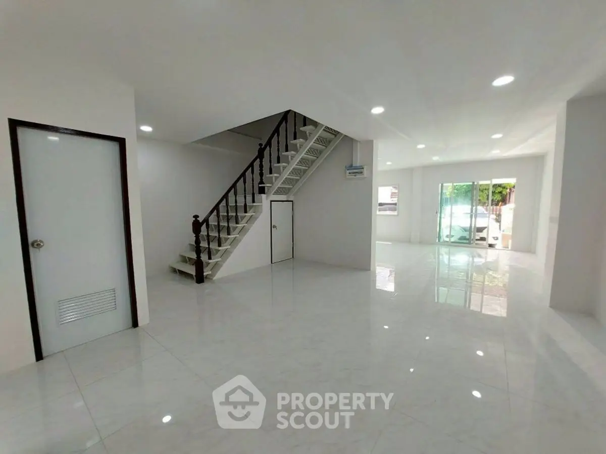 Spacious modern living area with sleek staircase and large windows for natural light.