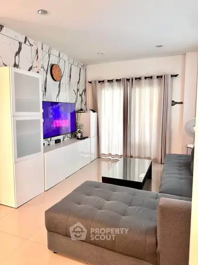 Modern living room with stylish decor and natural light, featuring a sleek sofa and entertainment center.