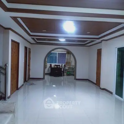 Spacious hallway with elegant ceiling design leading to a dining area, showcasing modern interior architecture.
