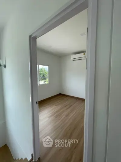 Spacious empty room with wooden flooring and air conditioning, perfect for customization.