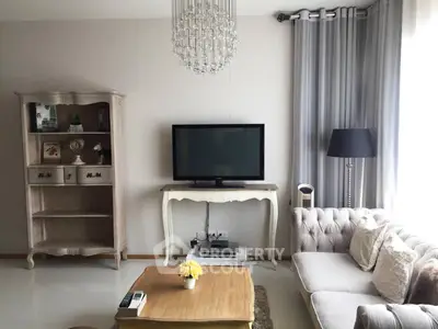 Elegant living room with classic decor, featuring a plush sofa, stylish chandelier, and a vintage TV stand.
