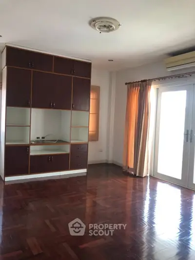 Spacious living room with built-in wooden cabinets and large window for natural light.