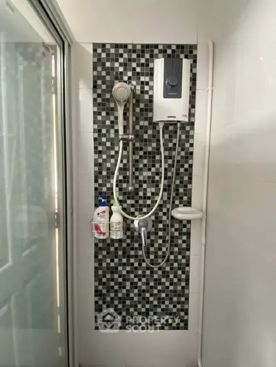 Modern bathroom shower area with stylish black and white tile design and water heater.