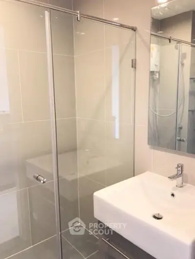 Modern bathroom with glass shower and sleek sink in contemporary apartment.
