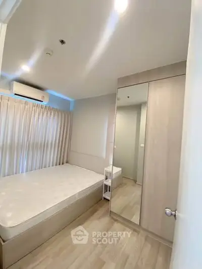 Modern bedroom with large window and mirrored wardrobe in stylish apartment.