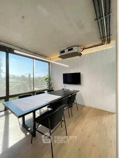 Modern office space with large windows and sleek design, featuring a conference table and chairs.