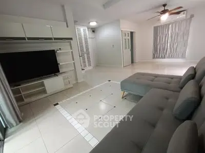 Spacious living room with modern gray sectional sofa and large TV unit, perfect for relaxation.