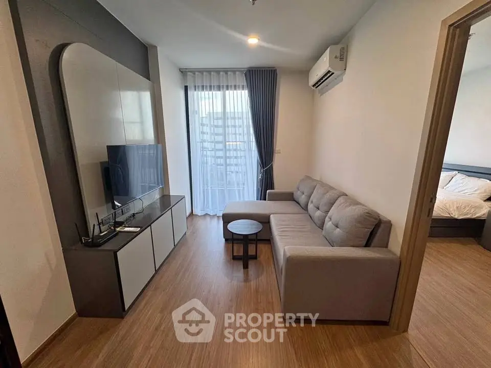 Modern living room with sleek furniture and natural light, adjacent to a cozy bedroom.