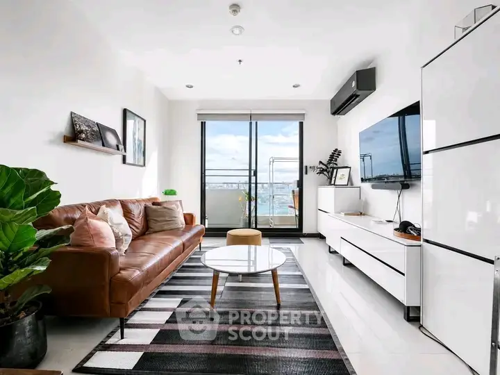 Modern living room with leather sofa, stylish decor, and balcony view in a bright apartment.