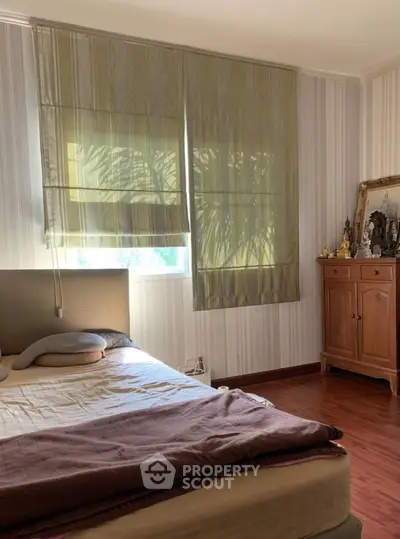 Cozy bedroom with natural light and wooden furniture, perfect for relaxation.