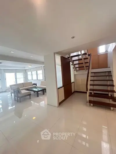 Spacious modern living room with elegant staircase and natural light