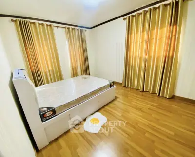 Spacious bedroom with elegant wooden flooring and golden curtains