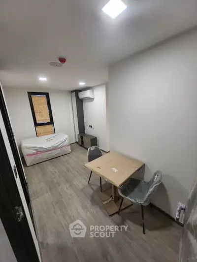 Modern minimalist bedroom with sleek flooring and compact furniture setup.