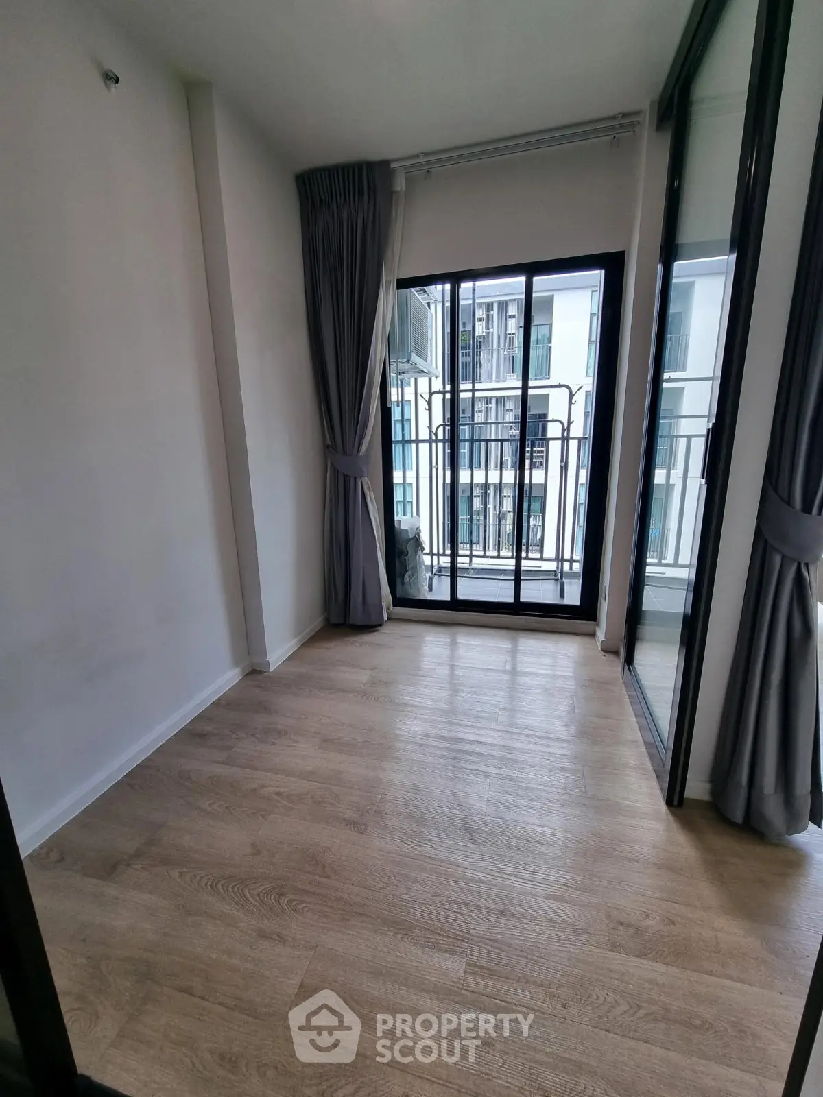 Spacious room with large windows and balcony access in modern apartment.