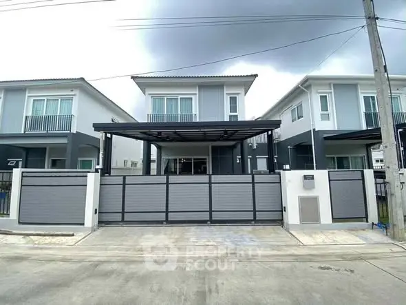 Modern two-story house with sleek design and gated driveway in suburban neighborhood.
