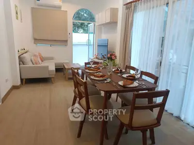 Elegant dining area with wooden table and cozy living space, perfect for family gatherings.