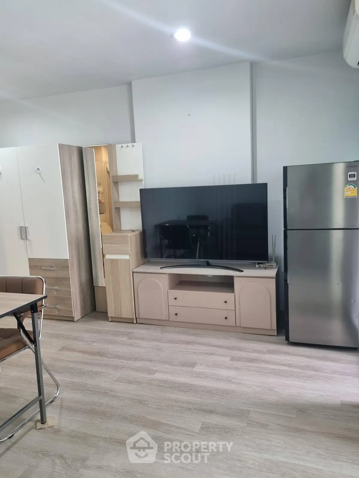 Modern living room with sleek TV unit and stainless steel fridge, perfect for contemporary living.